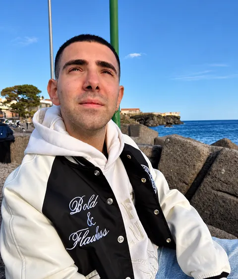 Il volto di Dario, seduto sugli scogli davanti al mare di Catania.